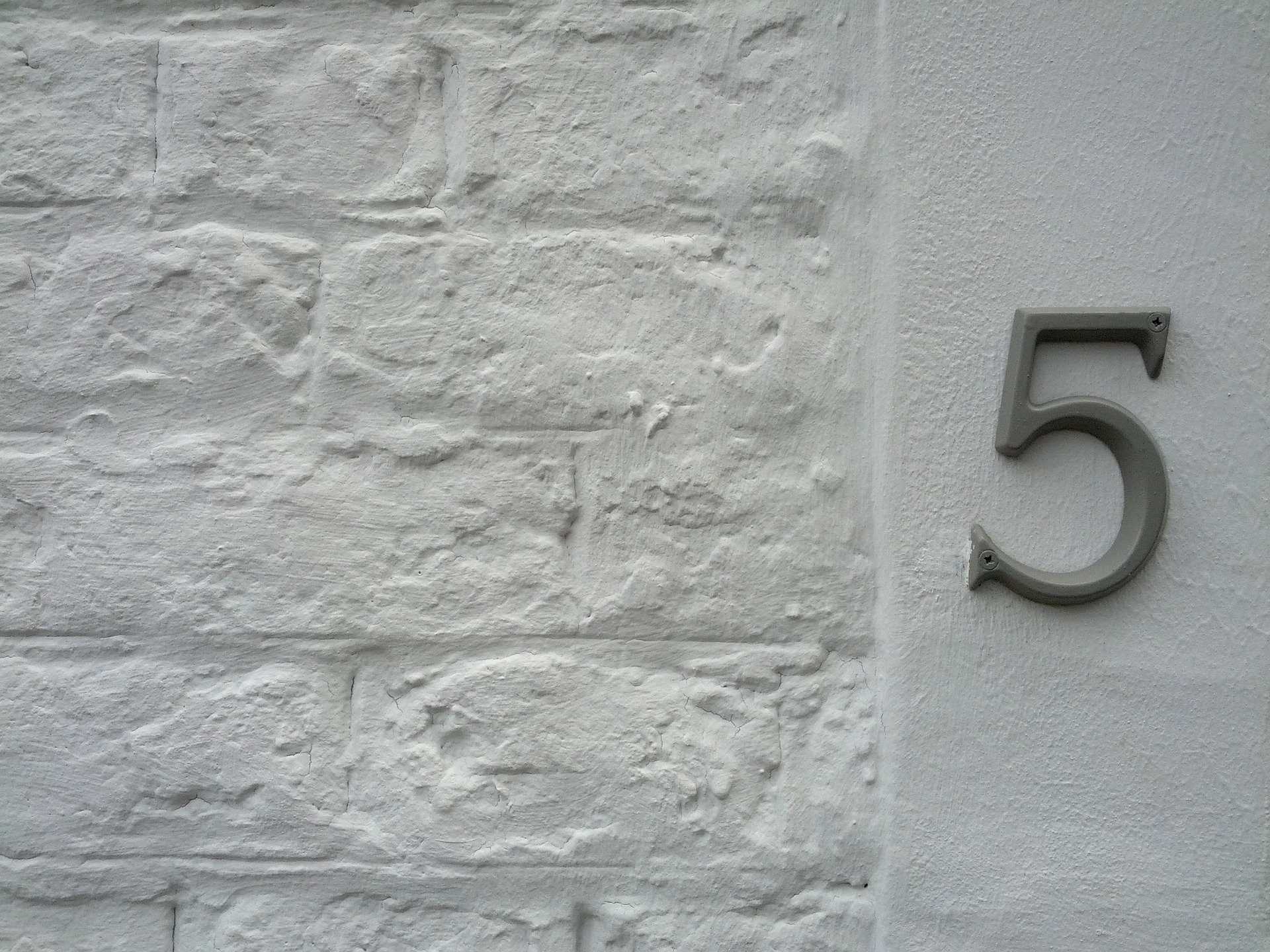 Número cinco pendurado em parede de casa branca