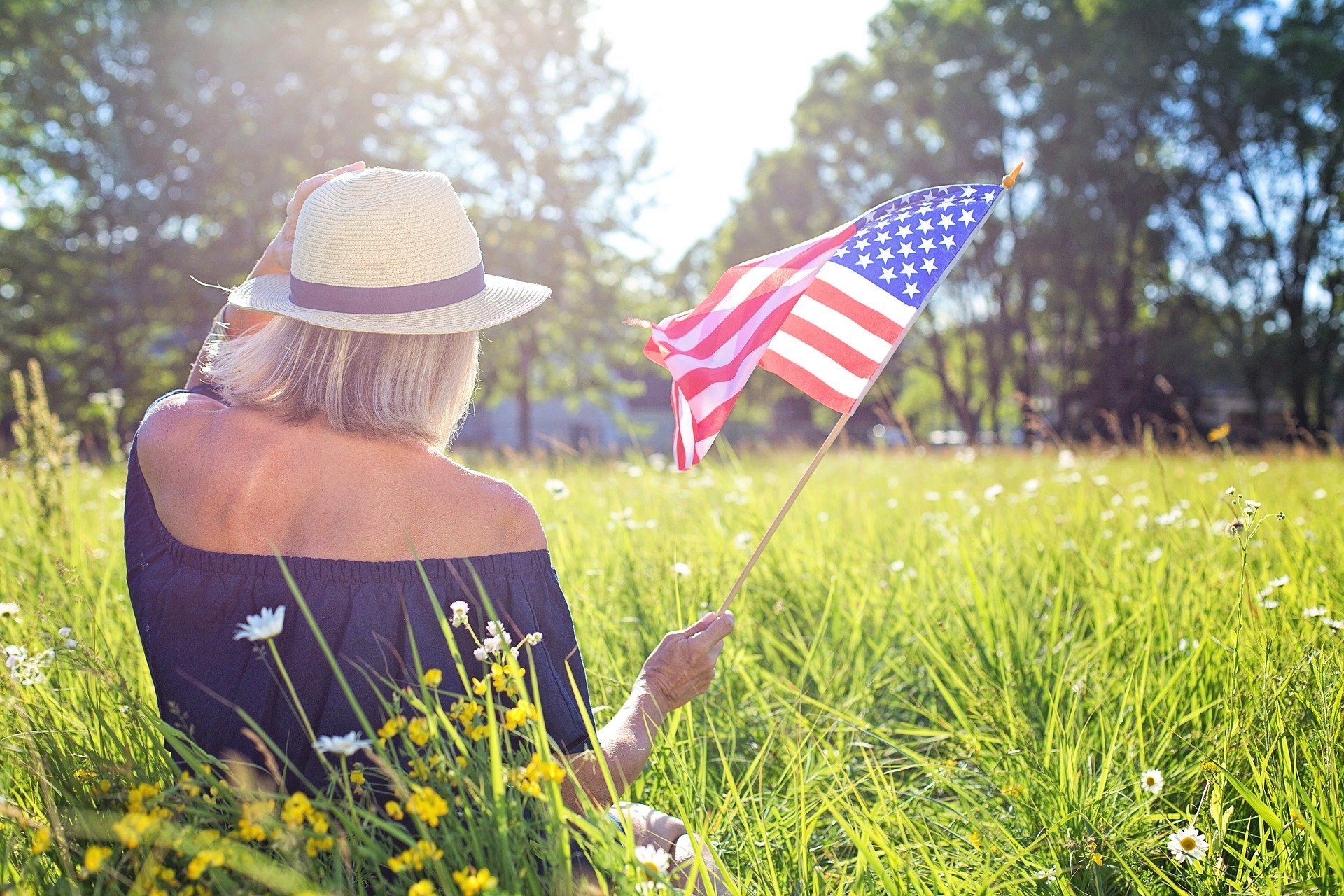 Mulher sentada em campo segurando a bandeira dos Estados Unidos