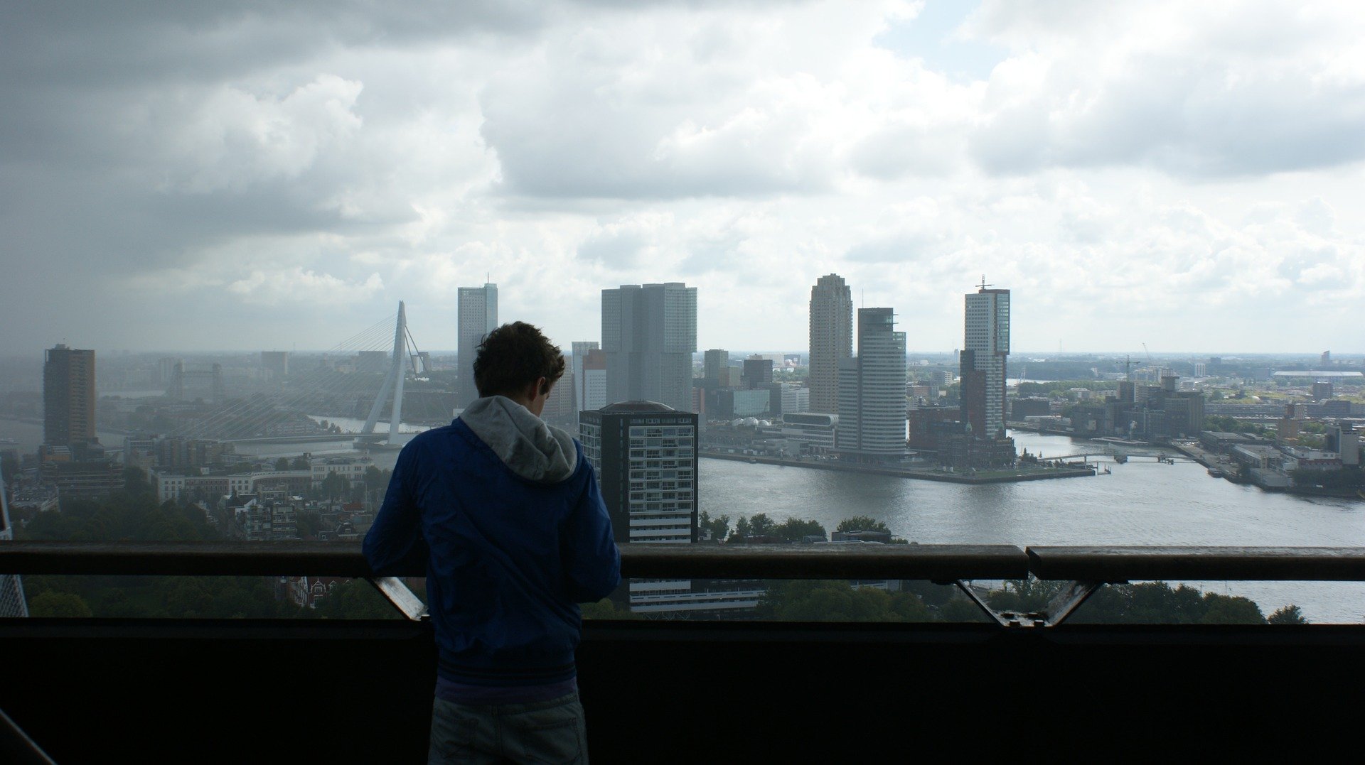 Homem observando paisagem de cidade em dia nublado