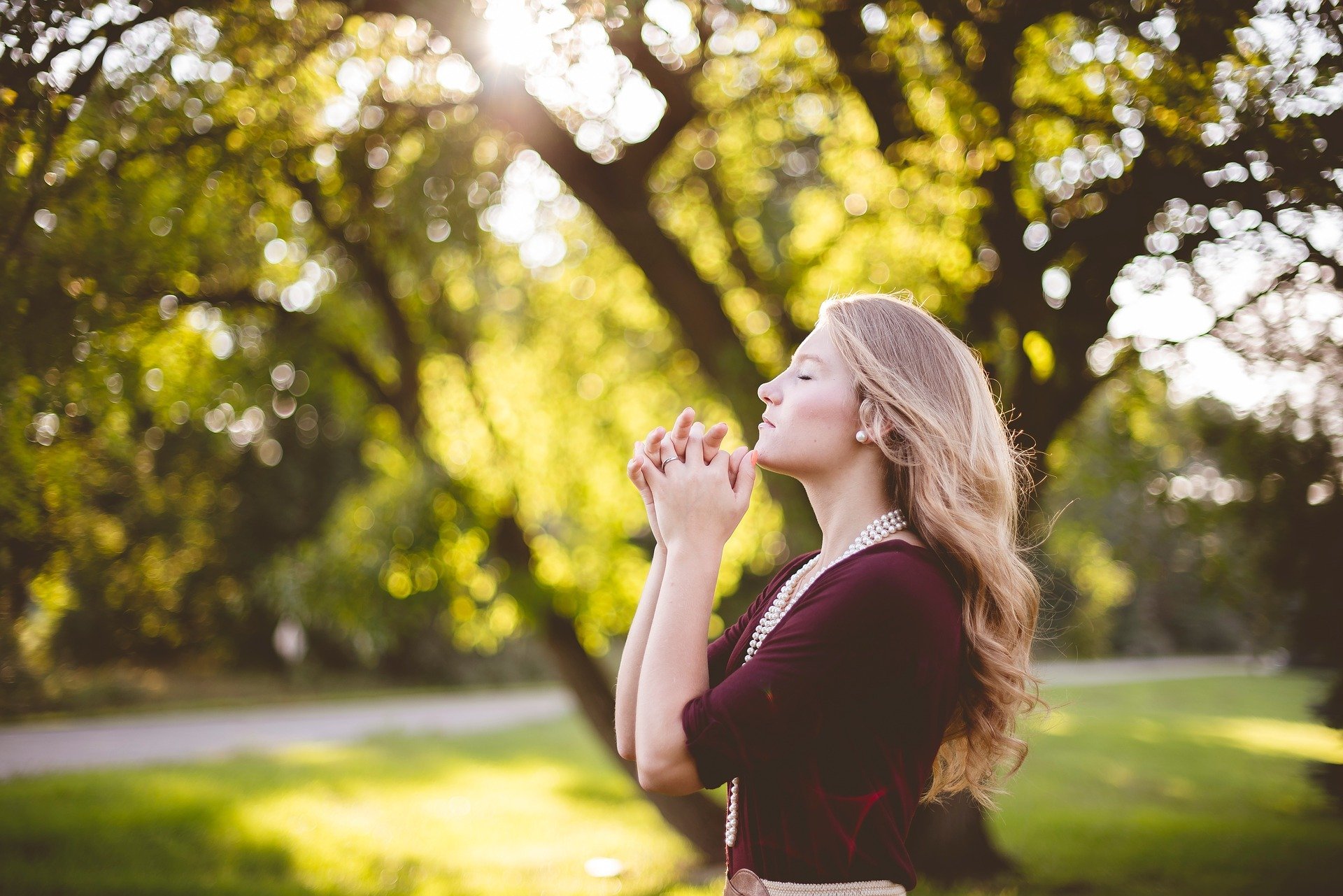Mulher de olhos fechados orando ao ar livre
