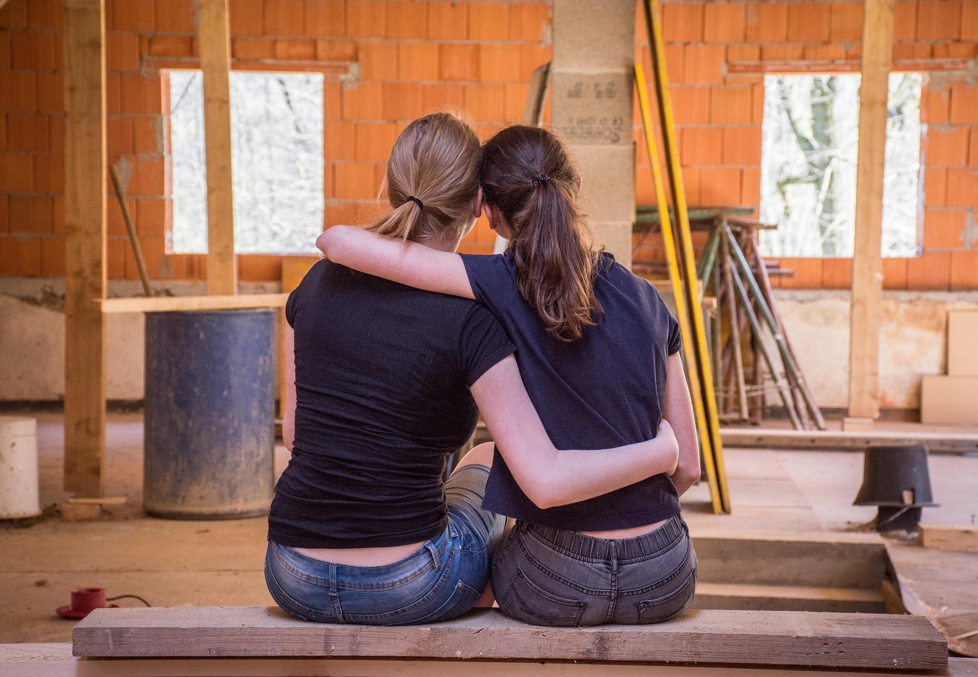 Amigas se abraçando em meio de casa em construção