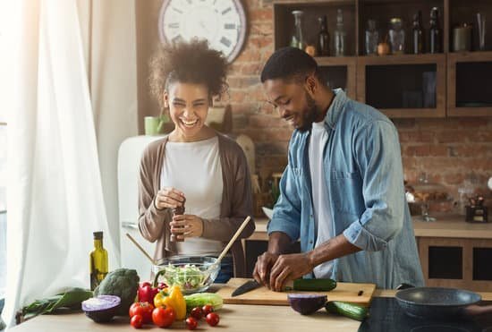 Homem e mulher cozinhando na mesa da cozinha e sorrindo