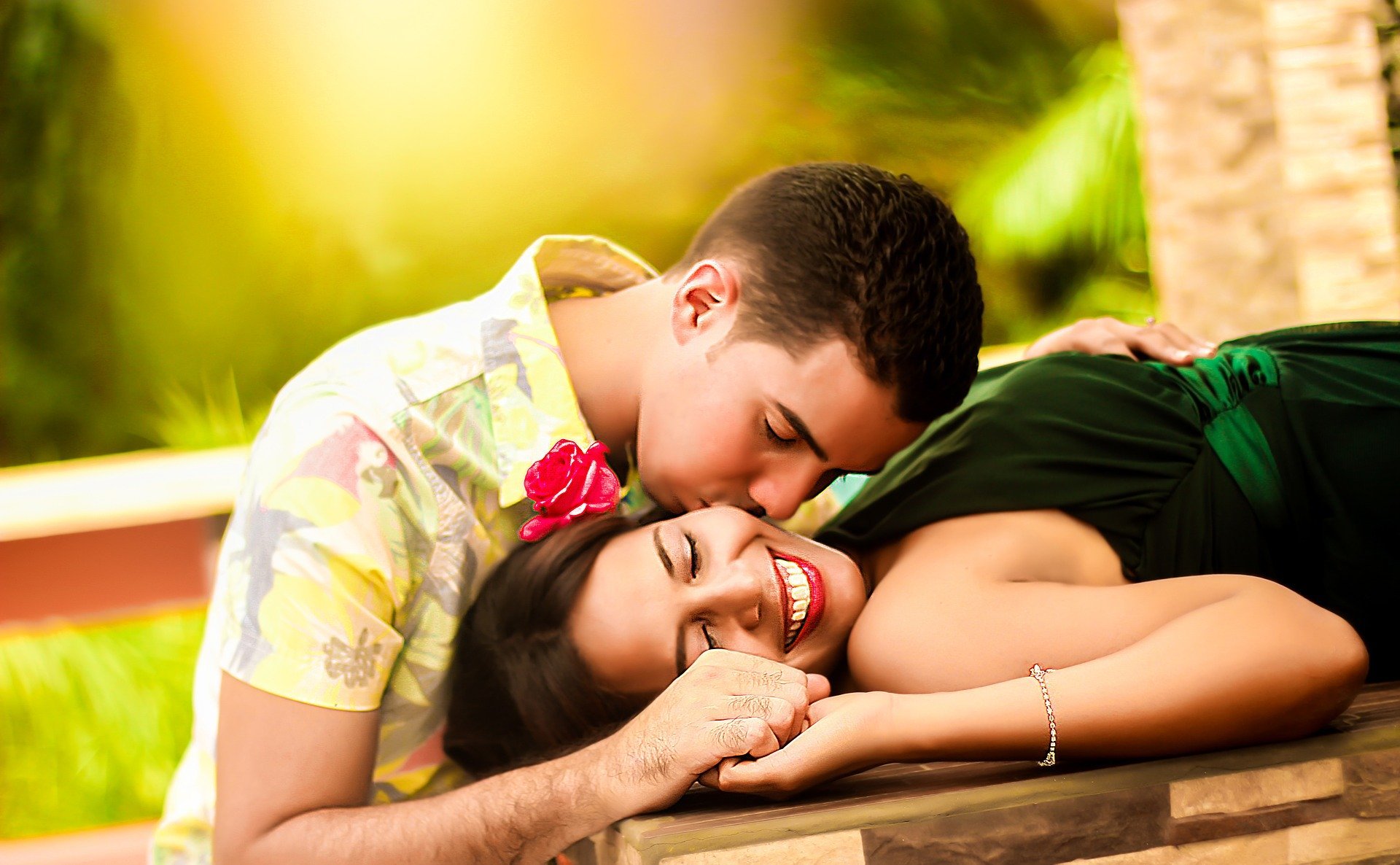 Homem beijando rosto de mulher sorridente deitada