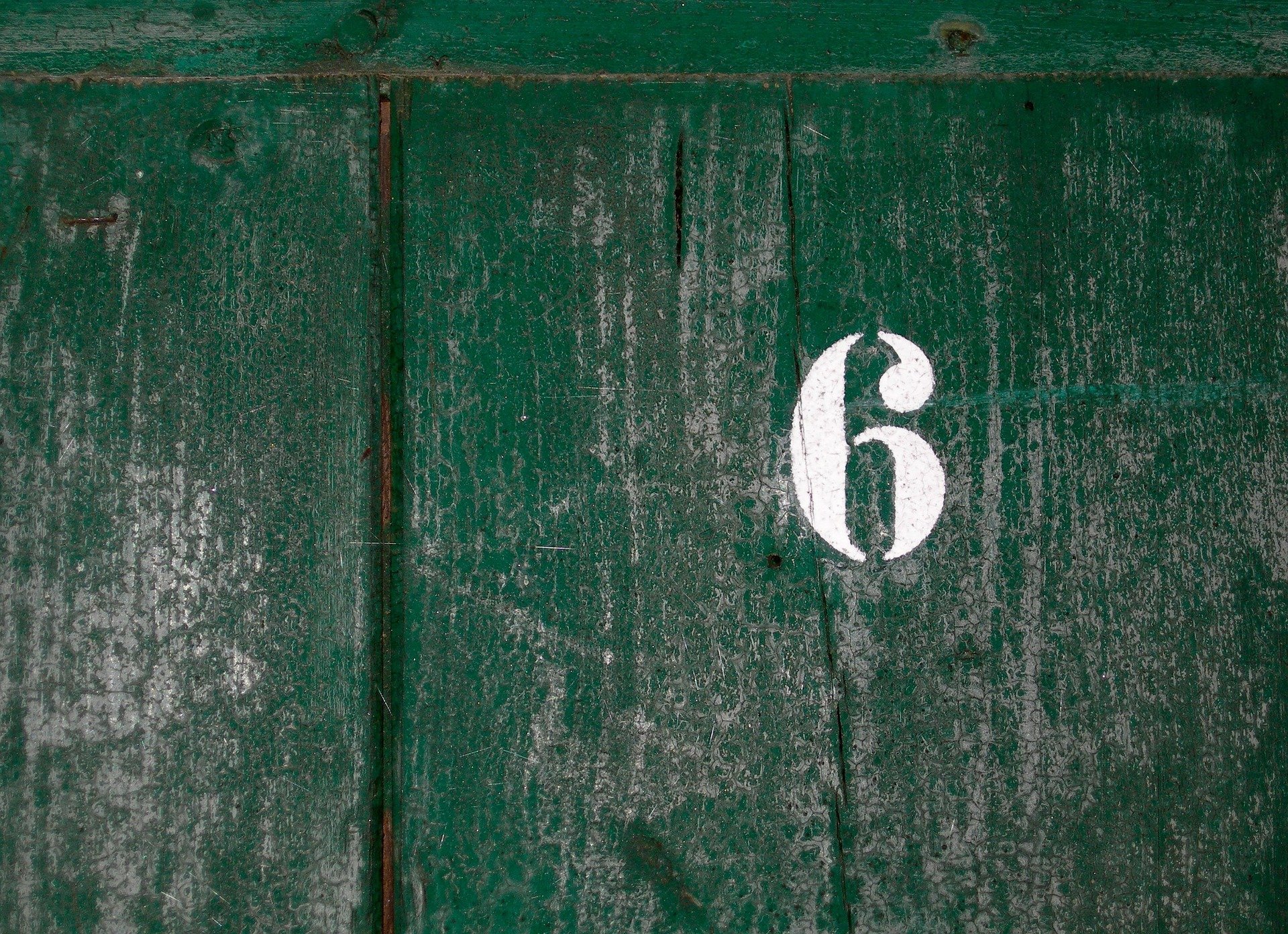 Número seis pintado de branco em porta verde
