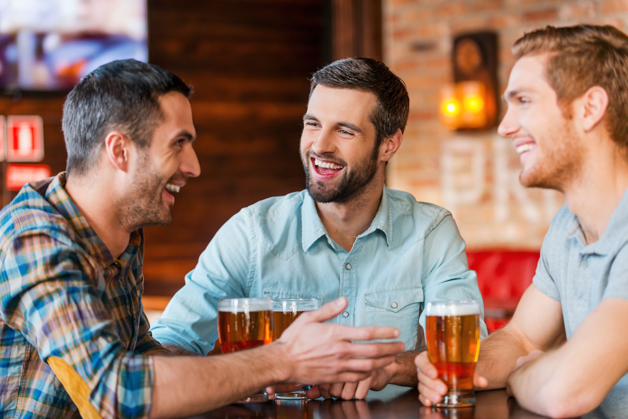 Amigos conversando, sorrindo e bebendo cerveja.
