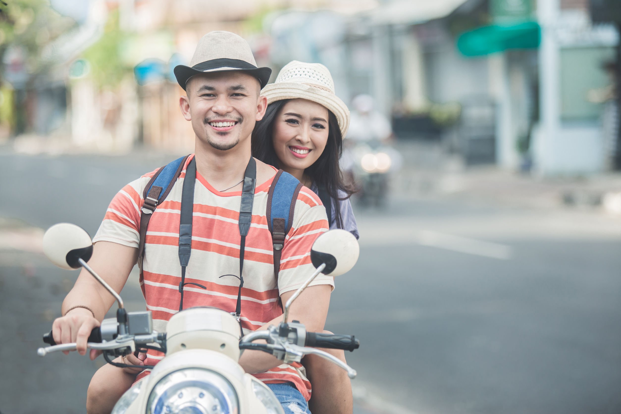 Casal de homem e mulher, vestidos como turistas, andando de moto