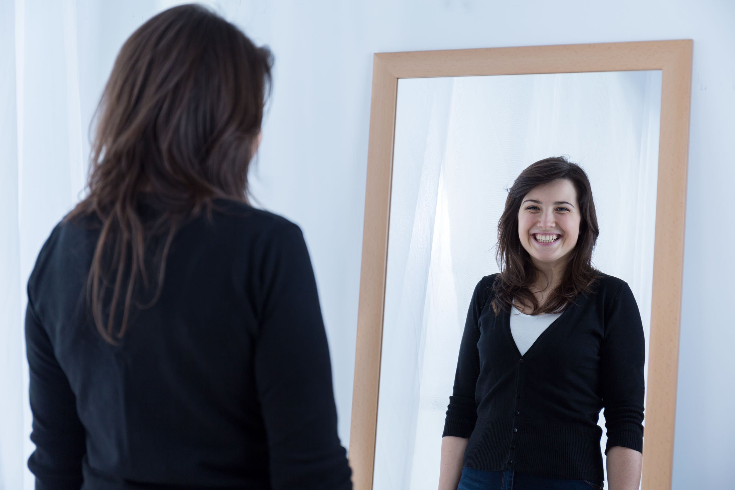 Mulher se olhando no espelho e sorrindo