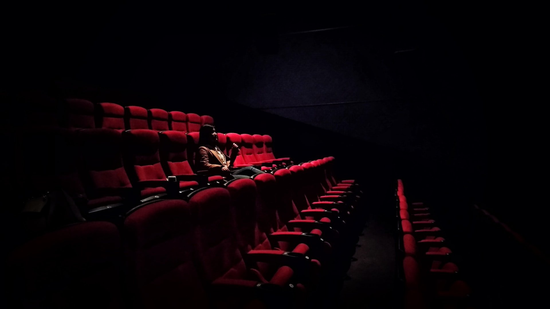 Mulher sentada numa sala de cinema escura.