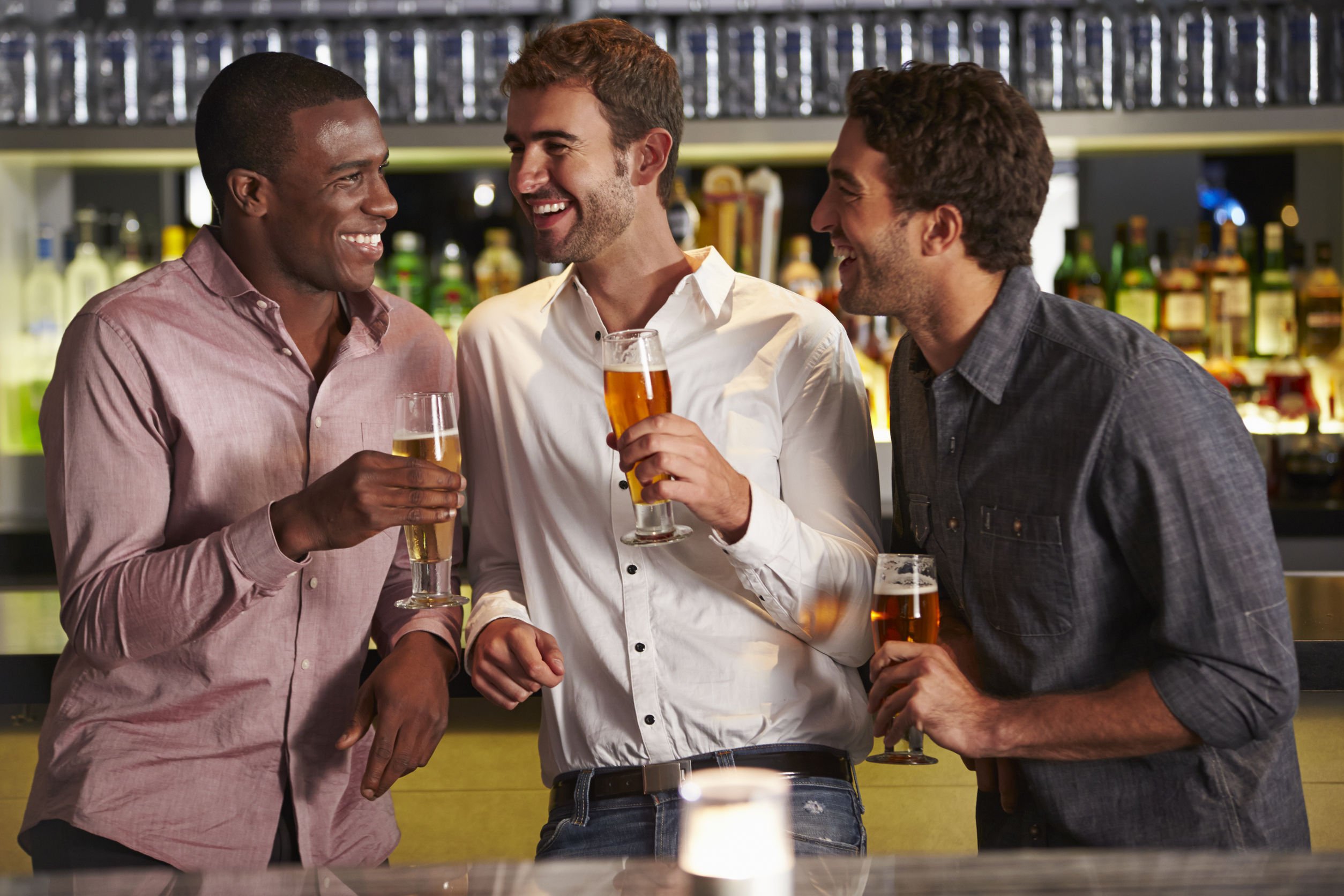 Homens sorrindo, conversando e bebendo cerveja.