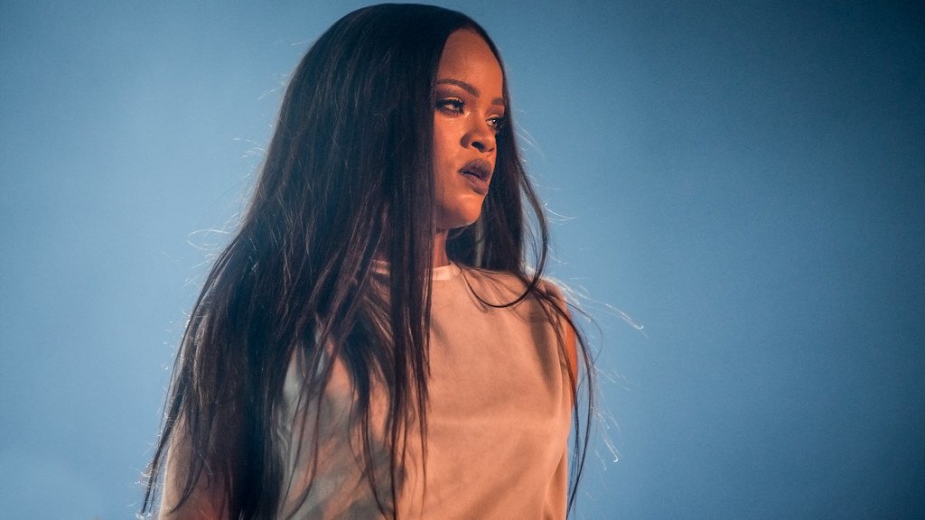 Cantora Rihanna com cabelos longos e pretos e expressão de determinação