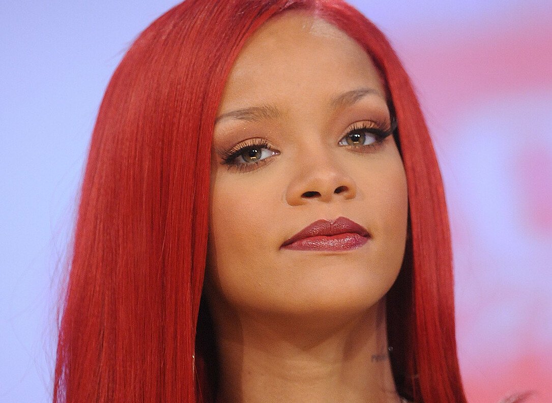 Cantora Rihanna com cabelos vermelhos e expressão calma.