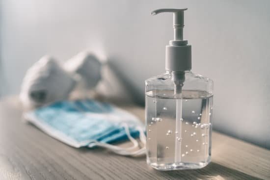 Maridav/Canva Frasco de álcool em gel ao lado de máscaras na mesa