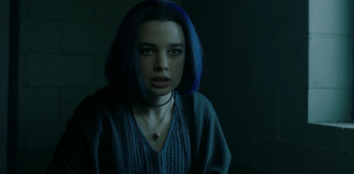 Ravena olhando para frente assustada em um quarto escuro