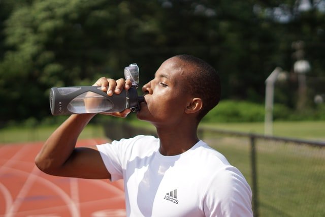 Homem negro bebendo água de garrafa.