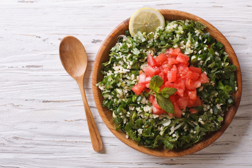 Tabule em cuia de madeira e colher de madeira ao lado