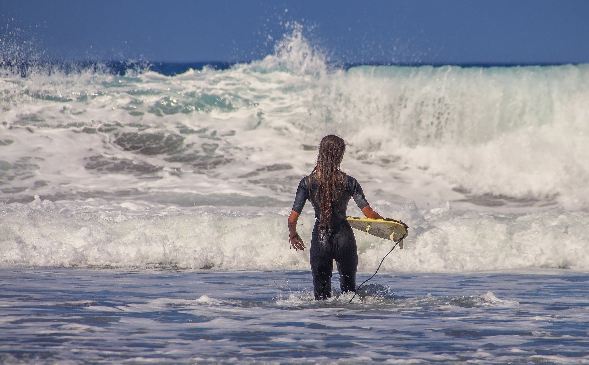 Mulher no mar, segurando prancha de surf.