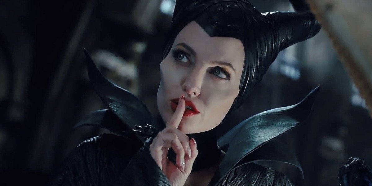 Angelina caracterizada como a personagem Malévola com o dedo na frente da boca