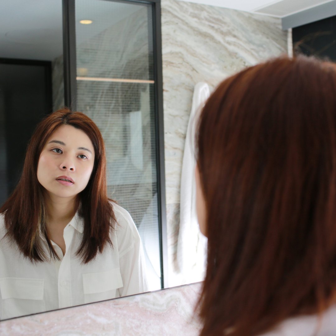 Imagem de uma mulher mau humorada se olhando no espelho