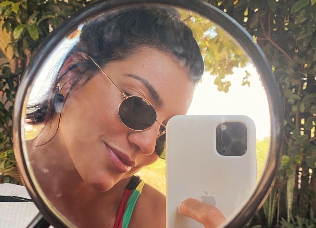 Influenciadora Gabi Prado de óculos escuros em frente ao espelho.