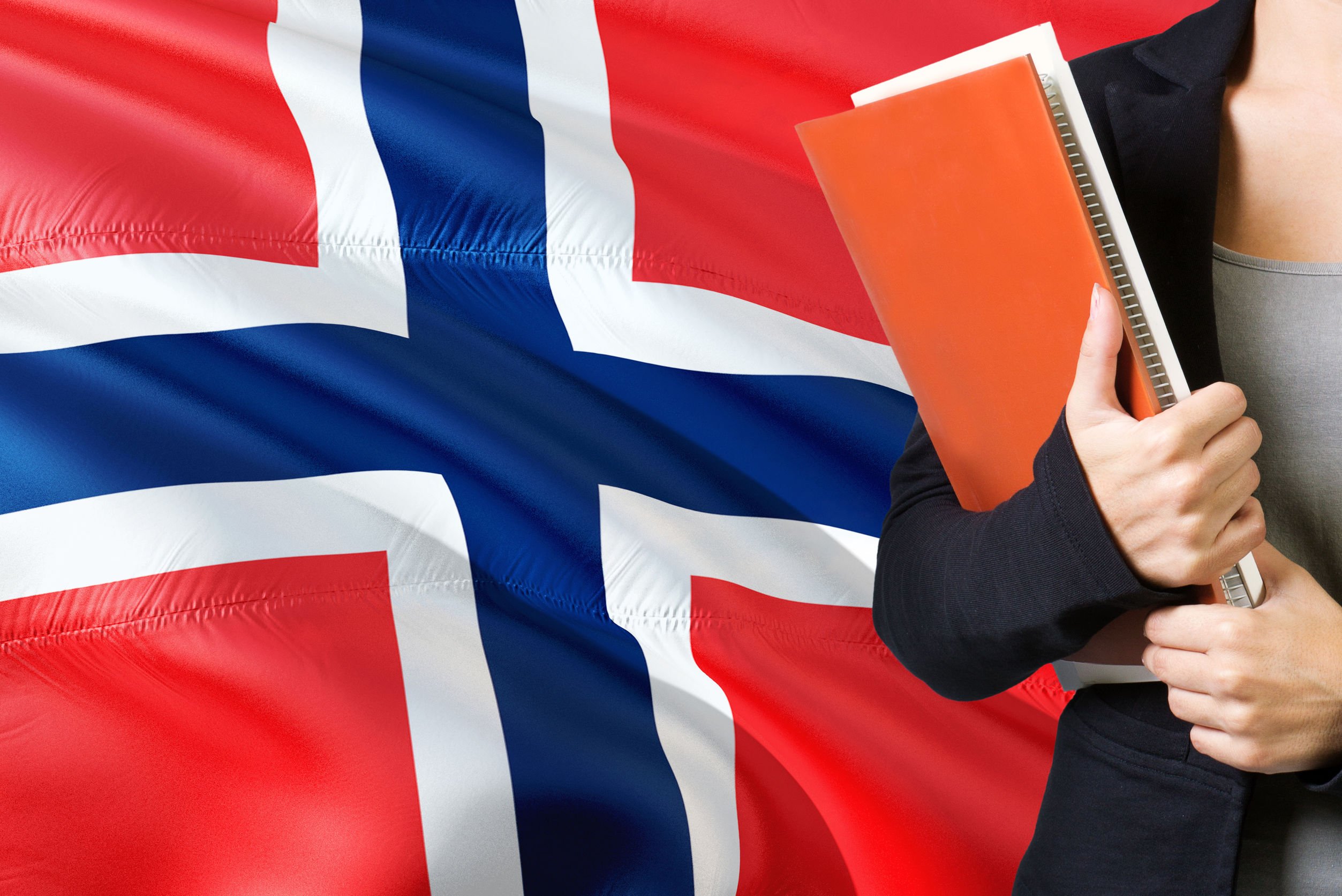 Estudante segurando caderno e bandeira da Noruega ao fundo.
