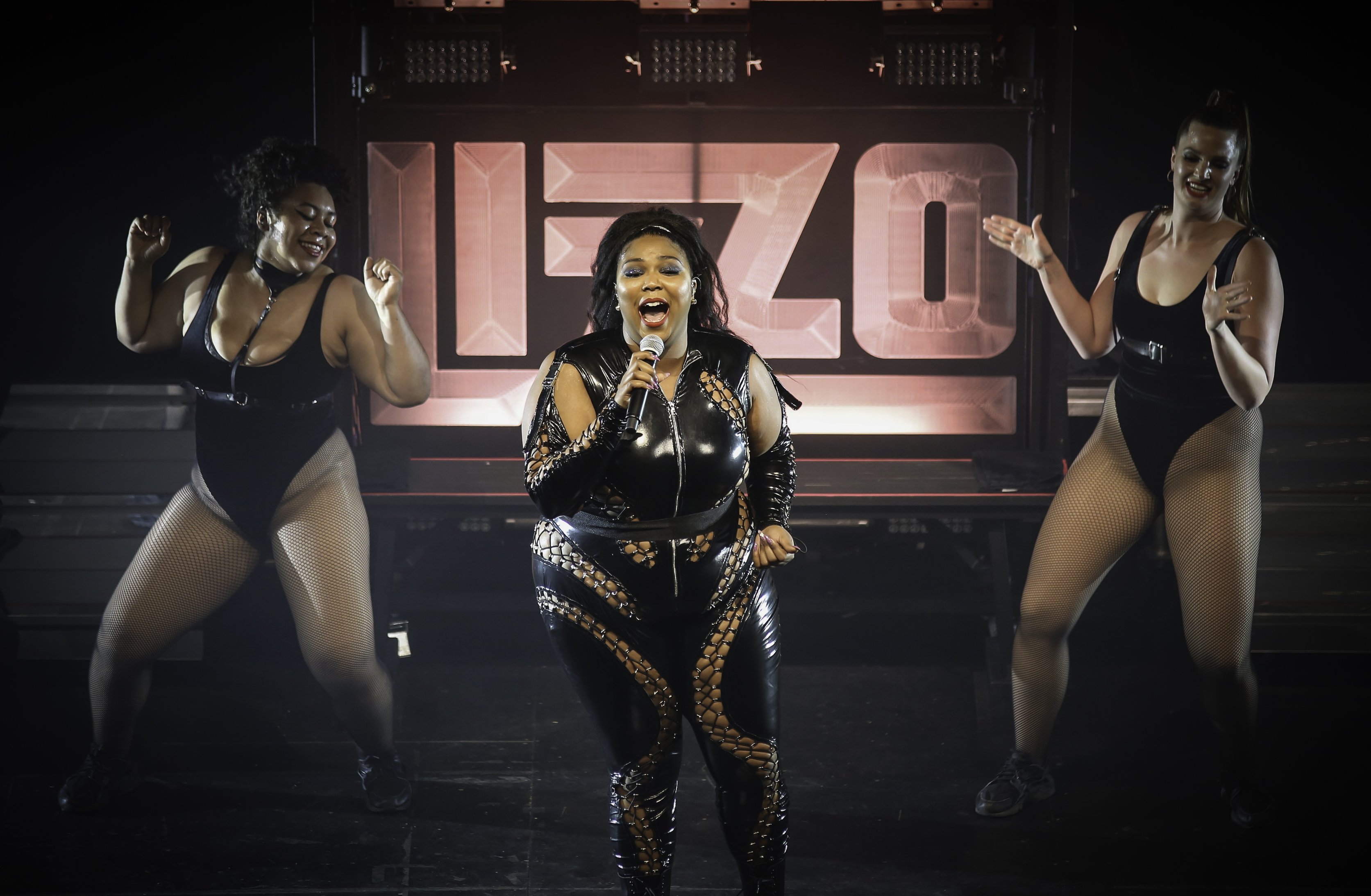 Lizzo em show cantando com duas dançarinas atrás