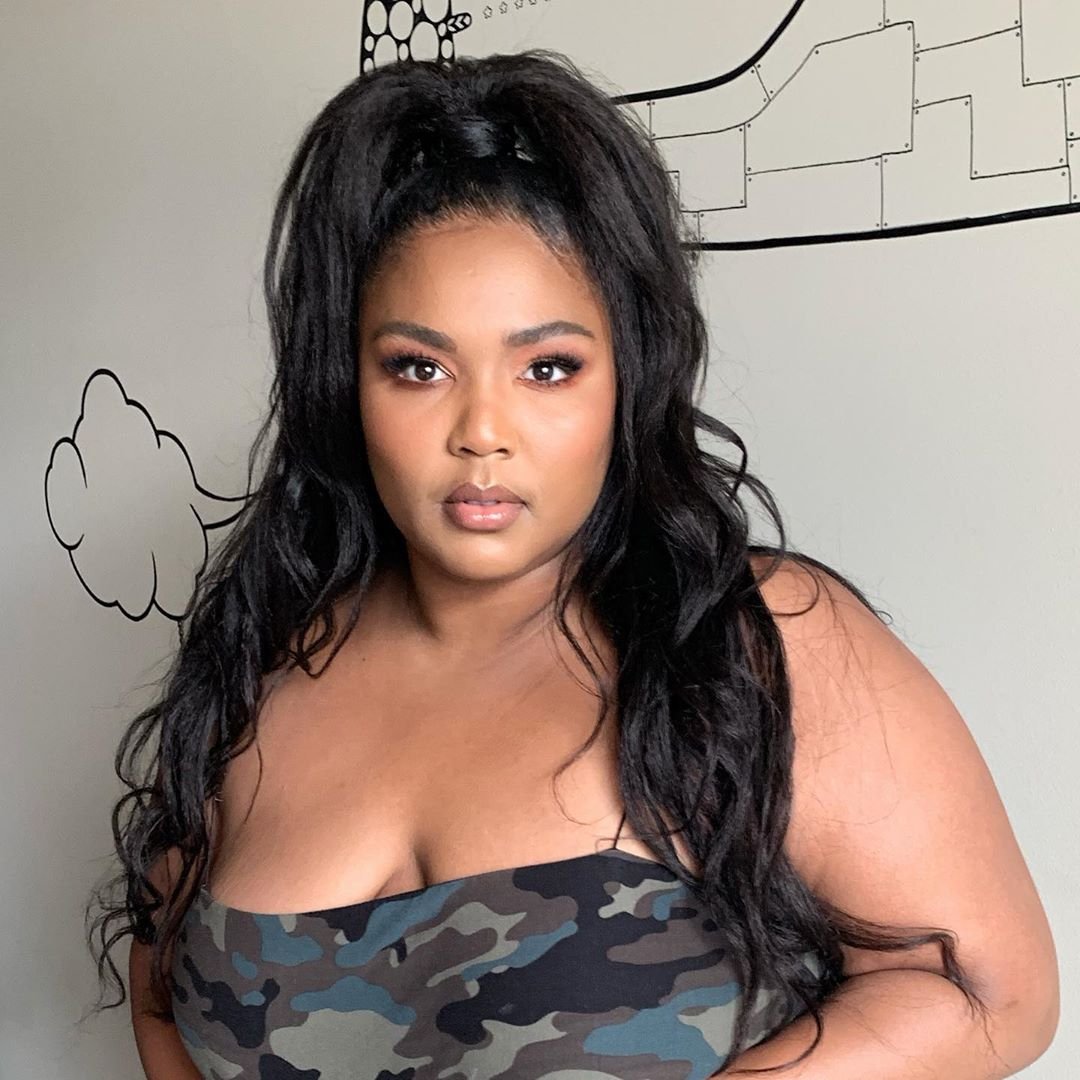 Lizzo em pé com cabelos presos usando blusa sem alça