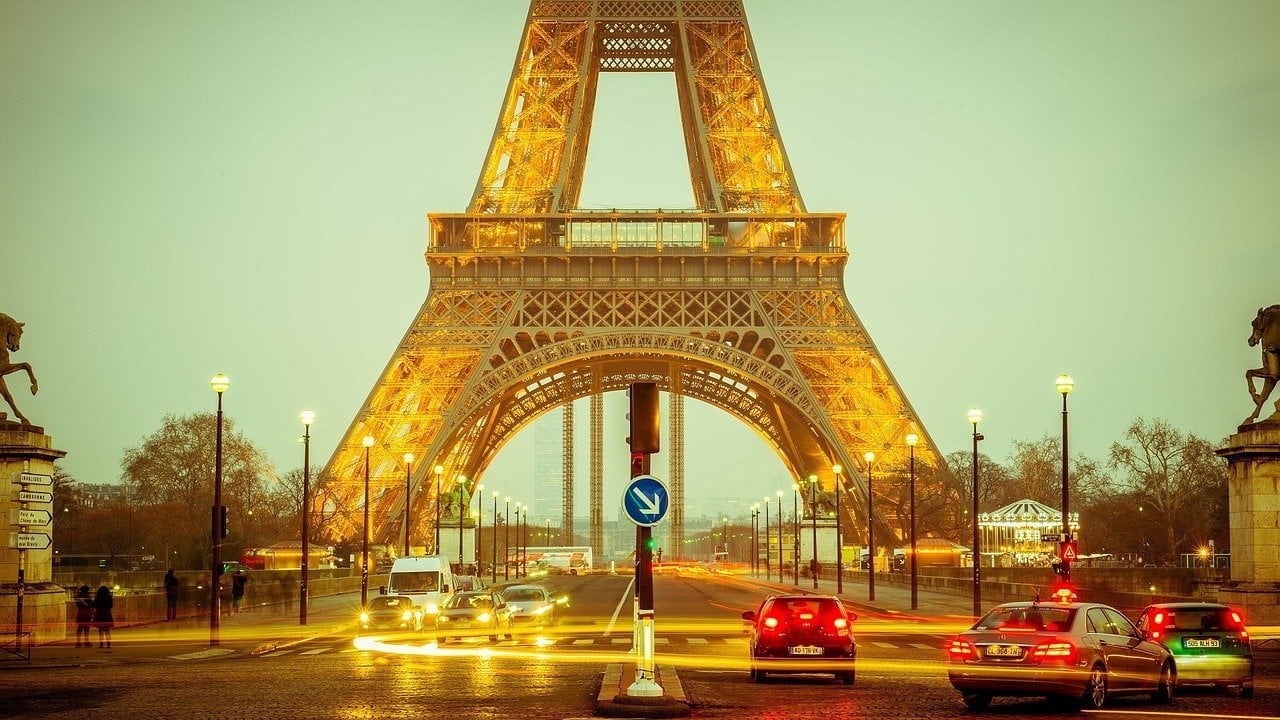 Rua com trânsito, em frente à torre Eiffel
