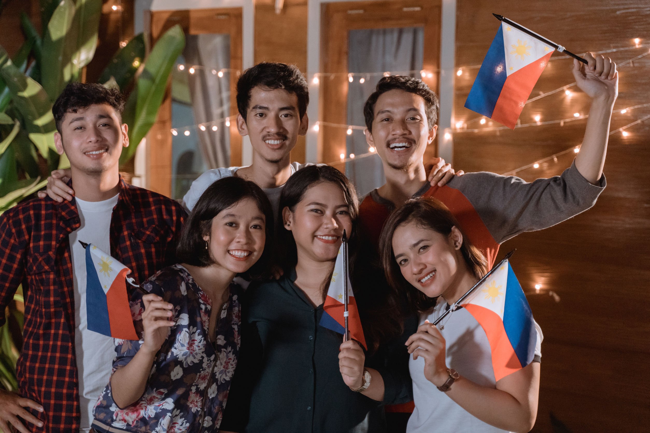 Pessoas sorrindo e segurando bandeira da Filipinas.