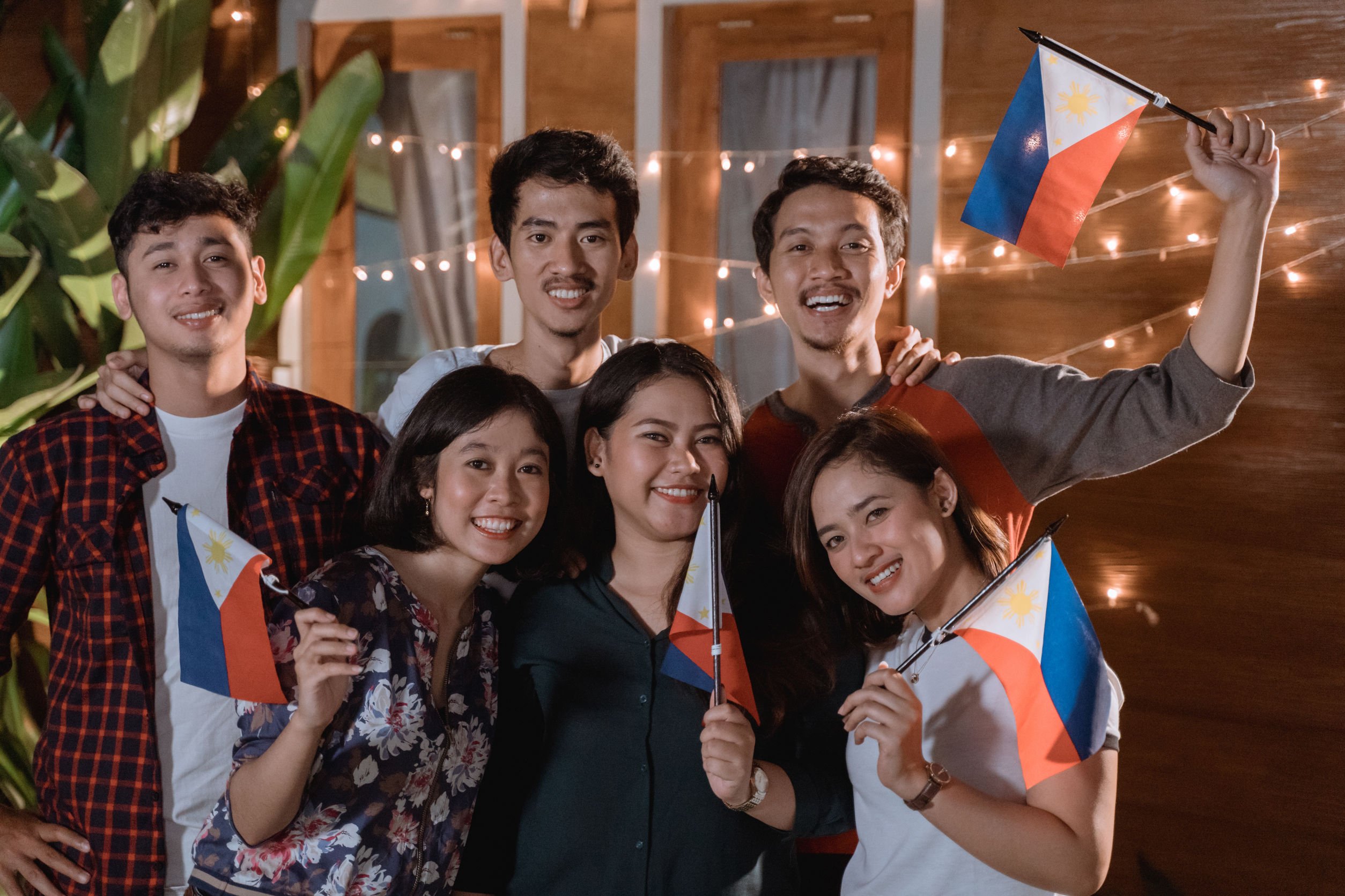 ferli/123RF Pessoas sorrindo e segurando bandeira da Filipinas.