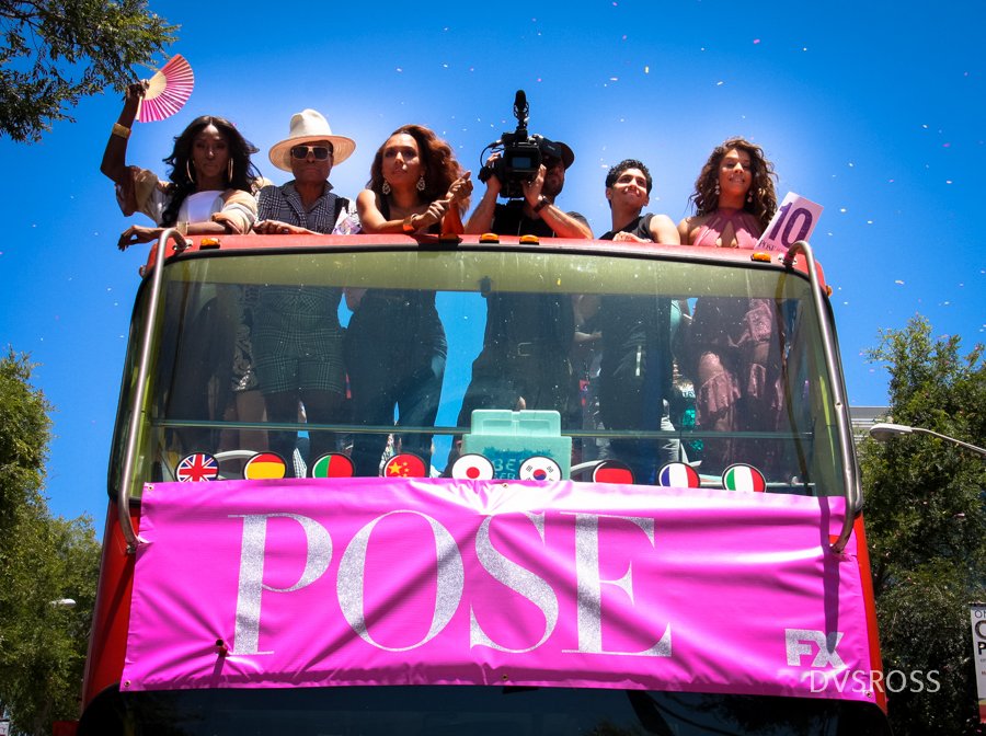 Foto dos personagens da série pose em cima de um carro alegórico durante marcha LGBT
