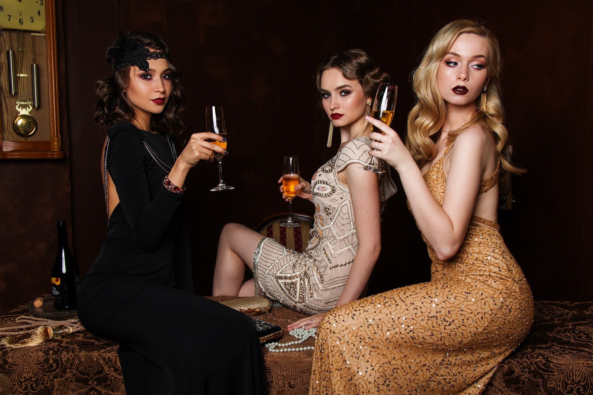 Mulheres vestidas pra festa, segurando taças de champanhe.