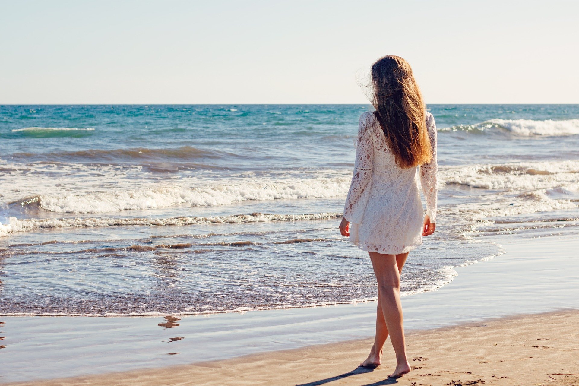 Mulher em pé em frente ao mar.