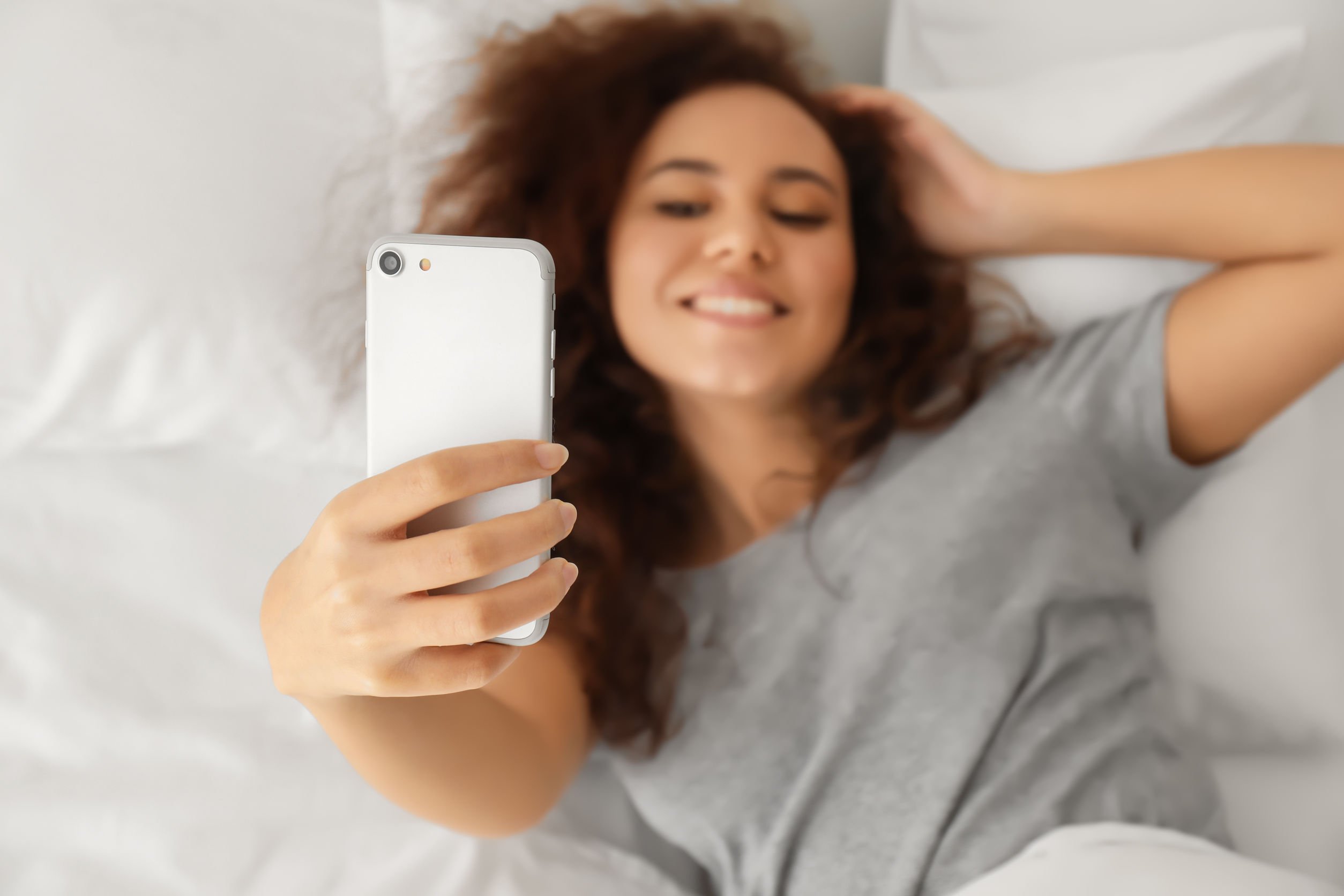 Mulher tirando selfie deitada.
