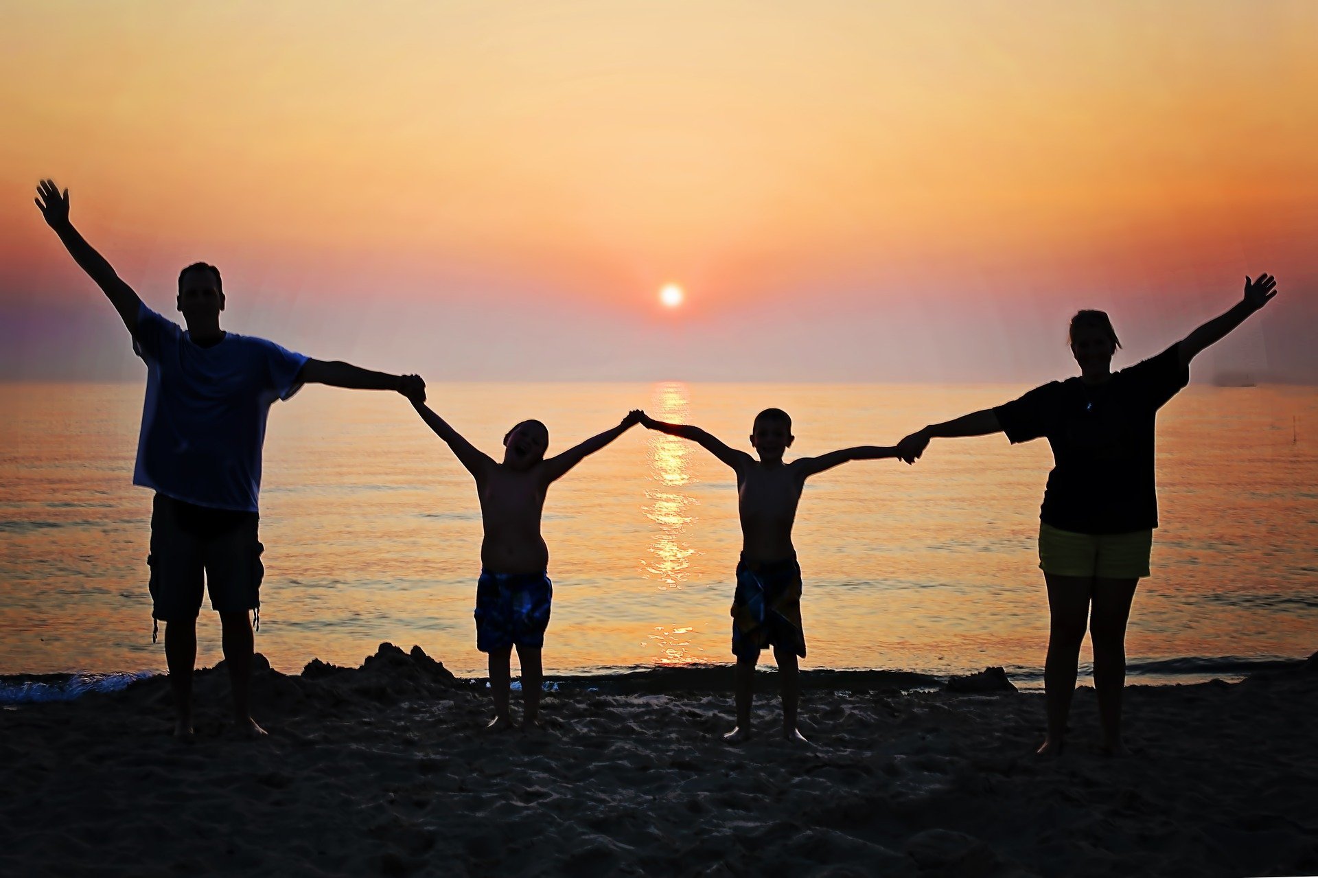 Silhueta de família junta de mãos dadas em praia.