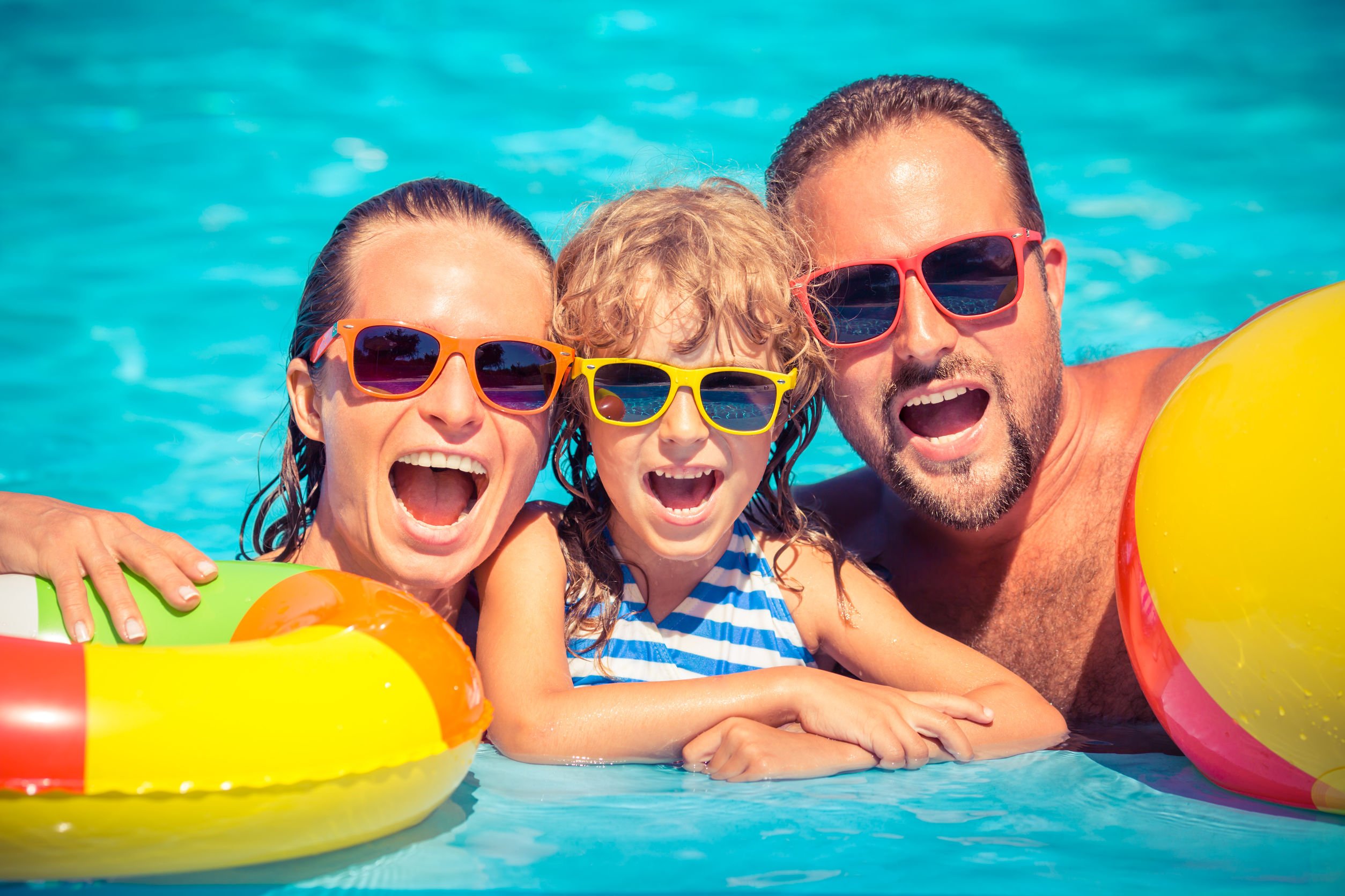 Família sorrindo em piscina.