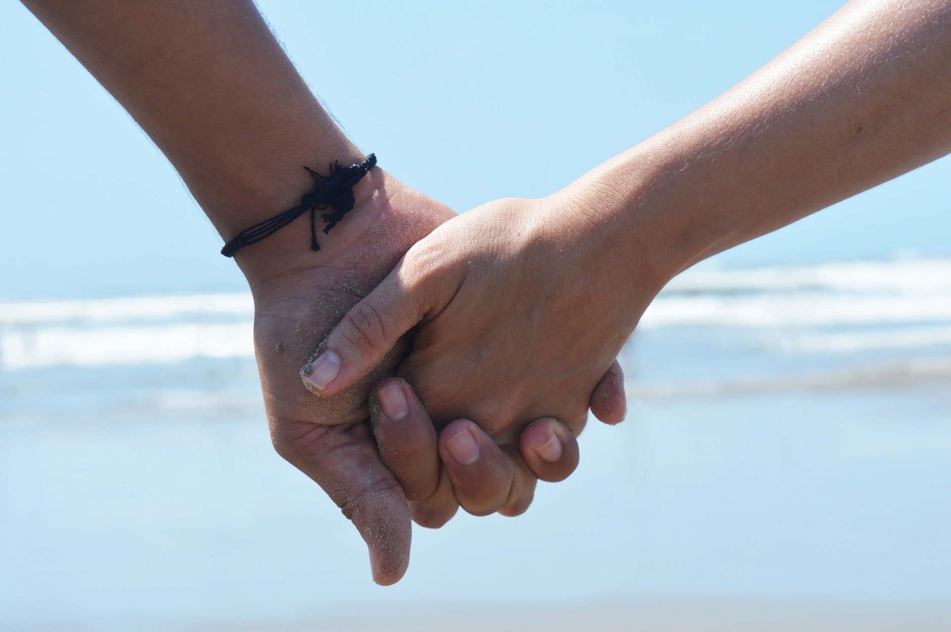 Casal de mãos dadas na praia.