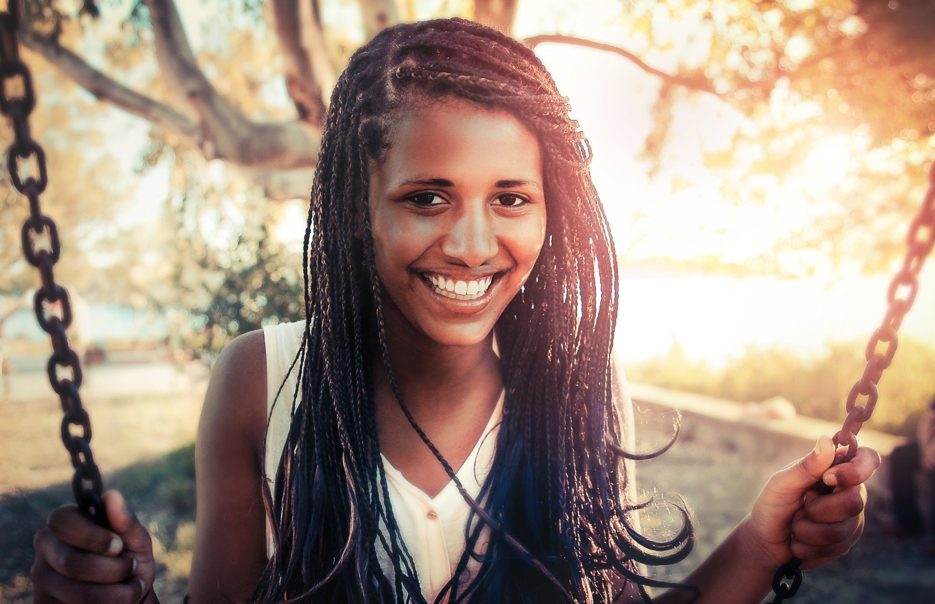 Mulher sorrindo, sentada em balanço.