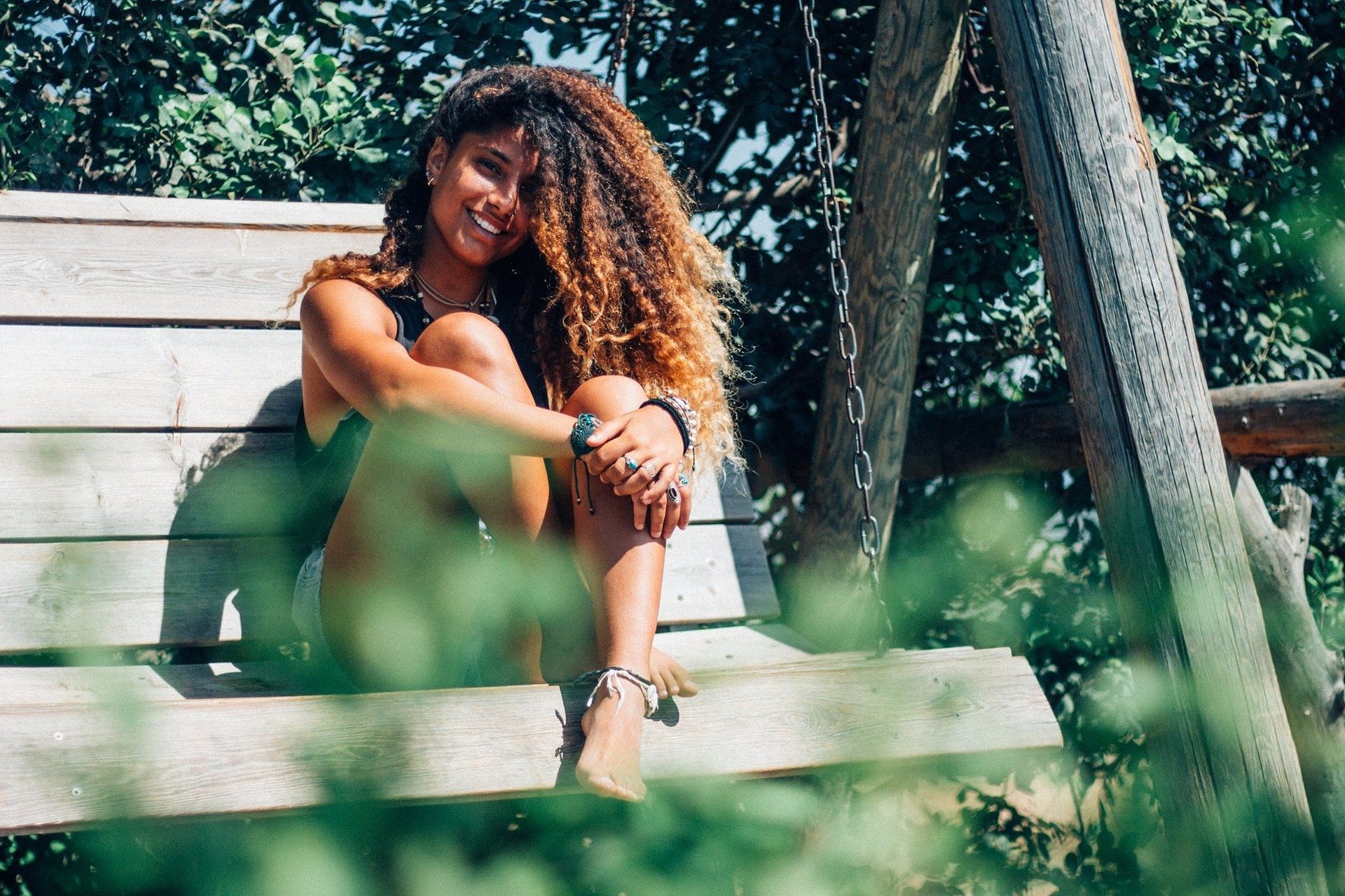 Mulher sentada em banco, sorrindo.