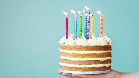 Pessoa segurando bolo de aniversário com velas