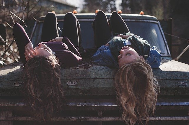 Mulheres deitadas em capô de carro