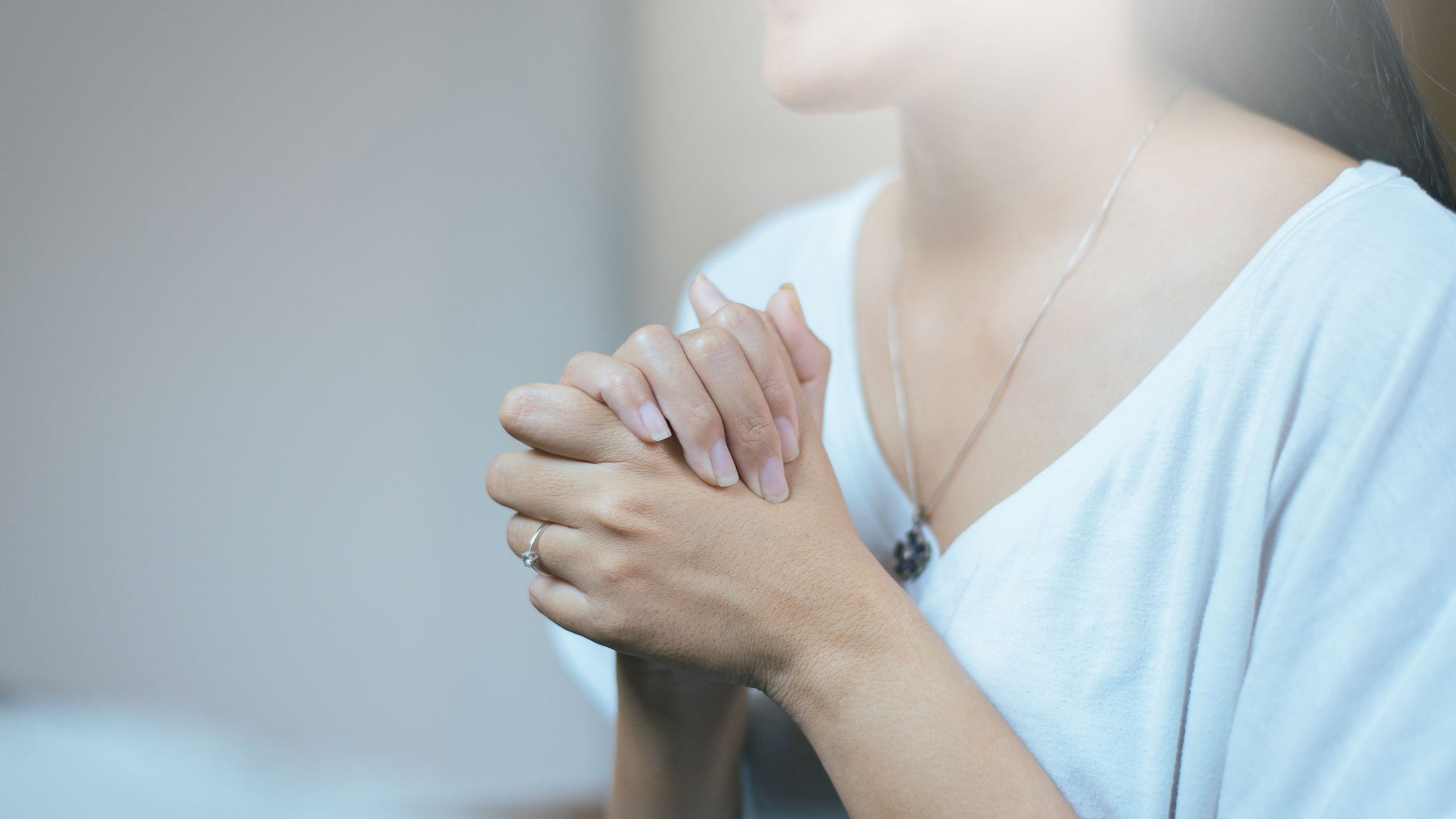 Mulher orando com as mãos unidas