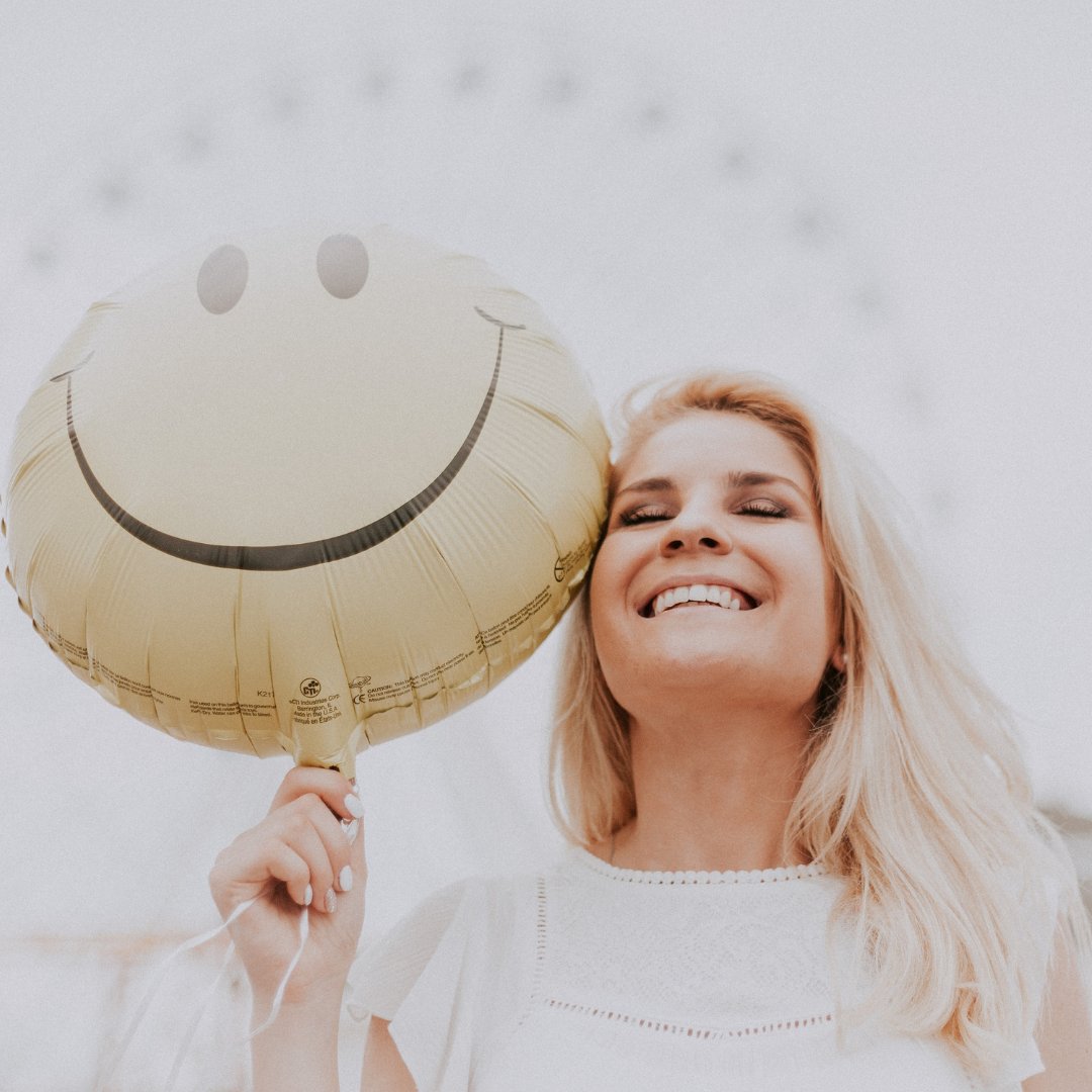 Mulher sorrindo segurando um balão de sorriso