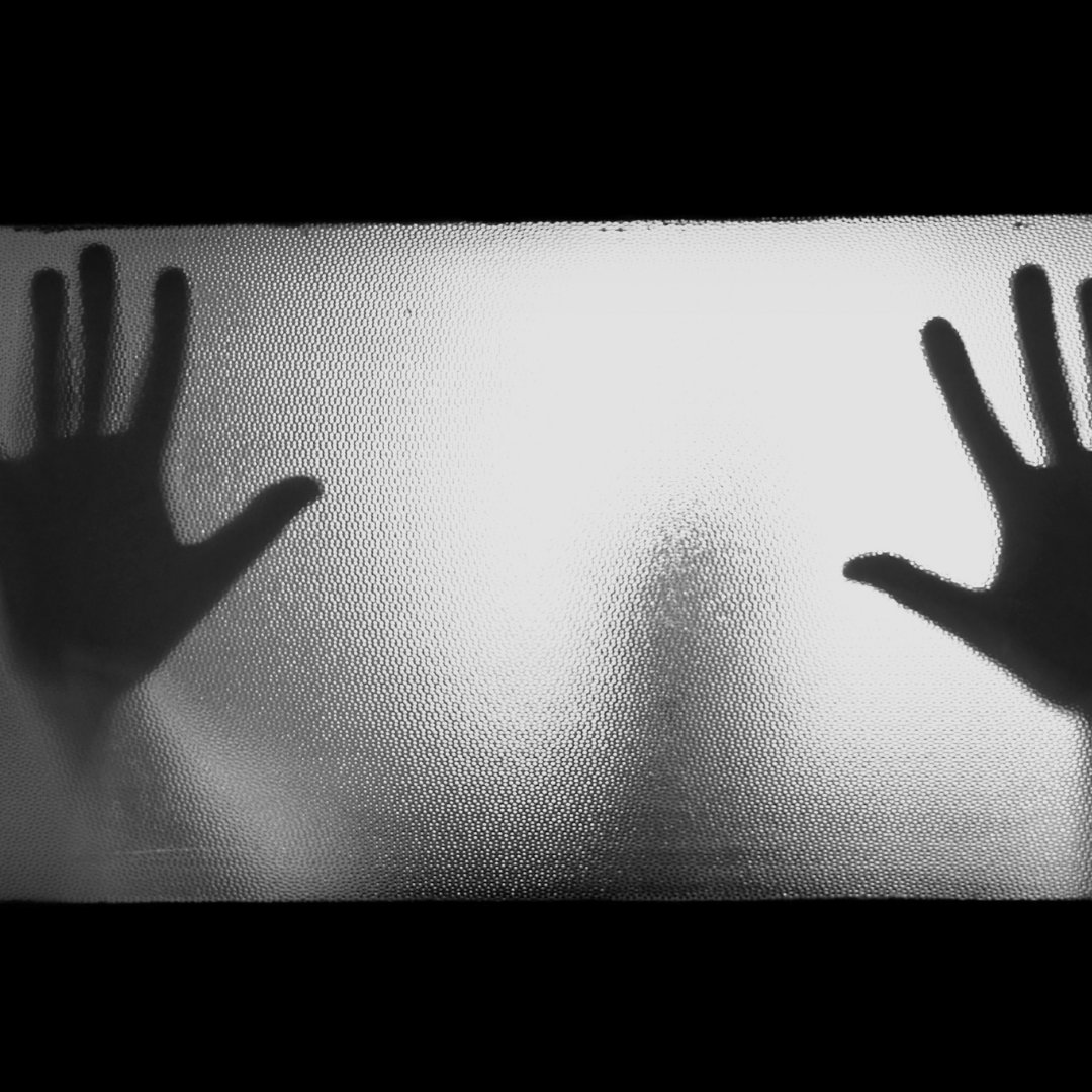 Imagem de uma pessoa apoiando as mãos em um vidro