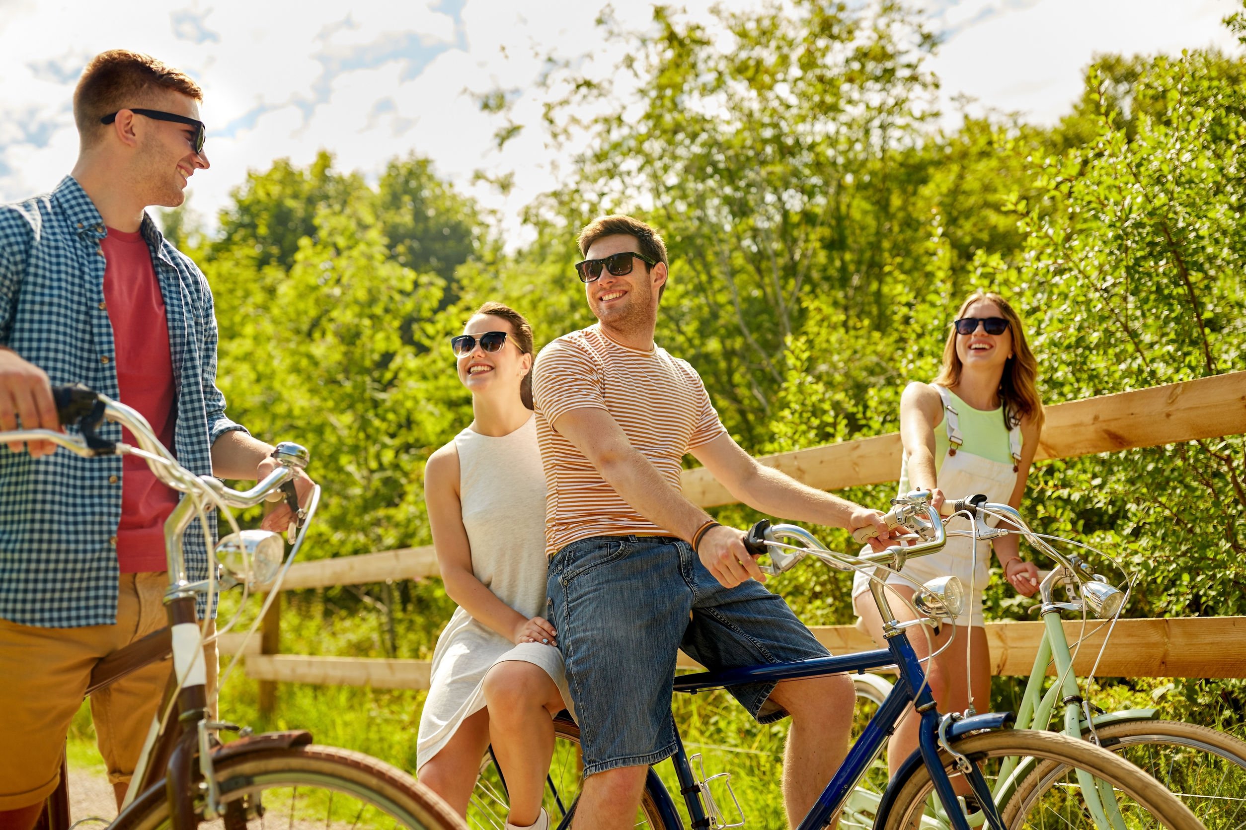 Grupo de amigos sorrindo, andando de bicicleta.
