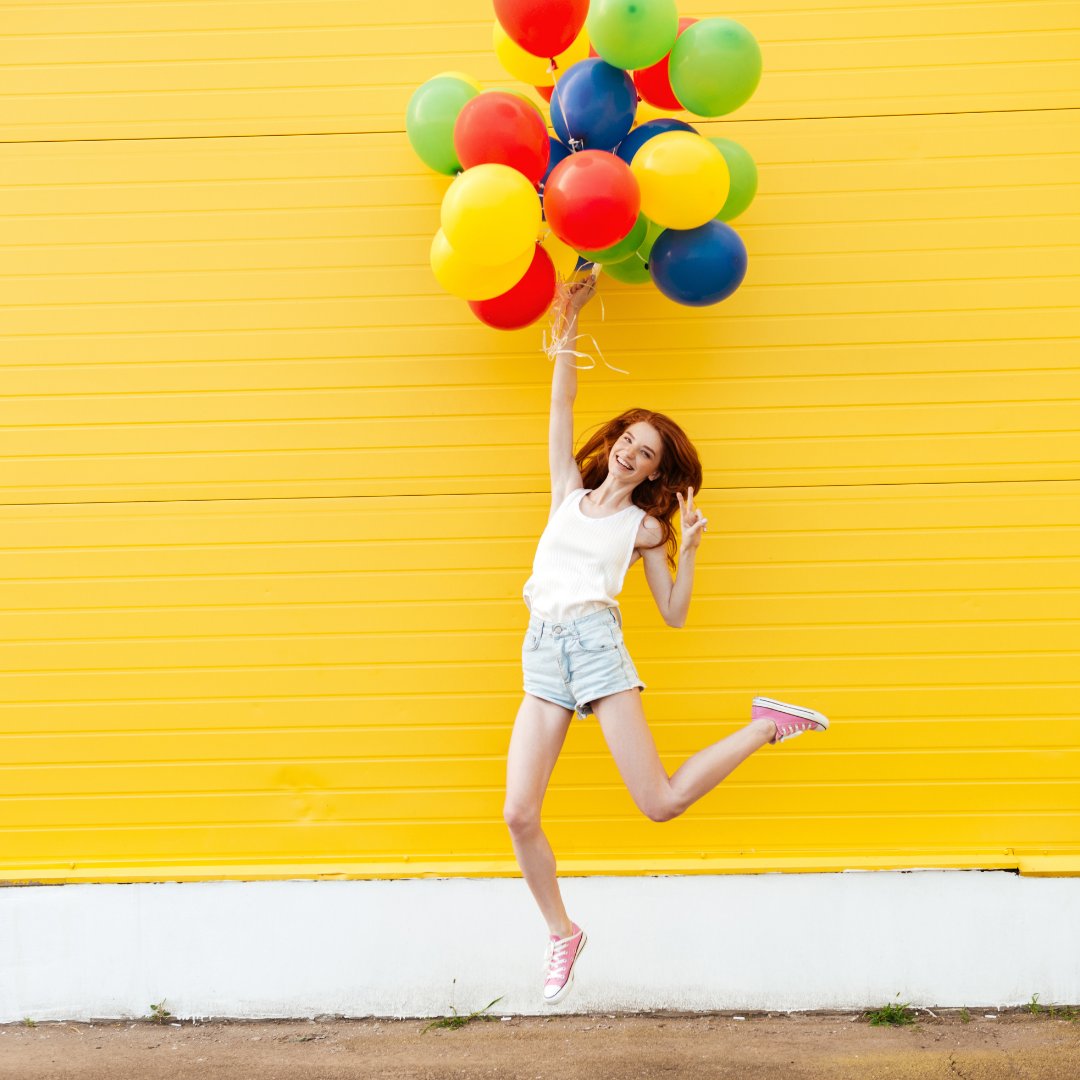 Imagem de uma menina segurando balões coloridos