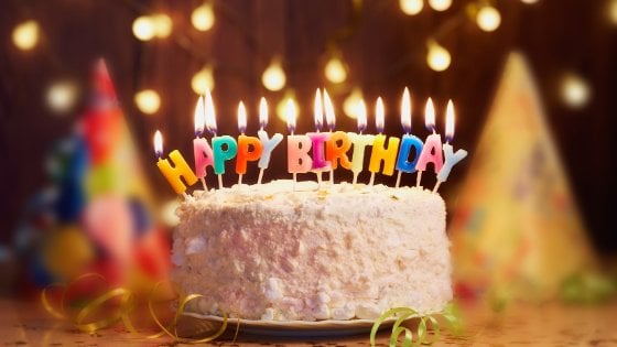 Bolo de aniversário com velas acesas escrito 'Feliz aniversário' em inglês
