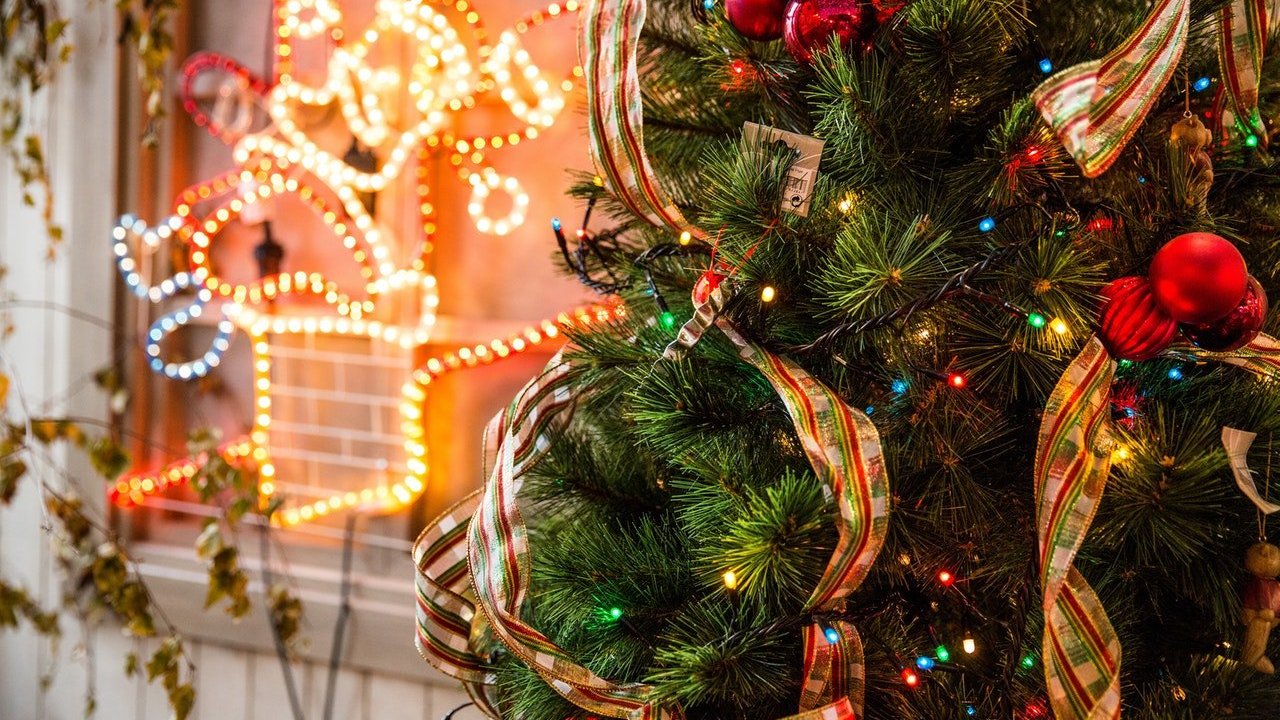 Recorte de uma árvore de natal decorada com vários enfeites em volta.