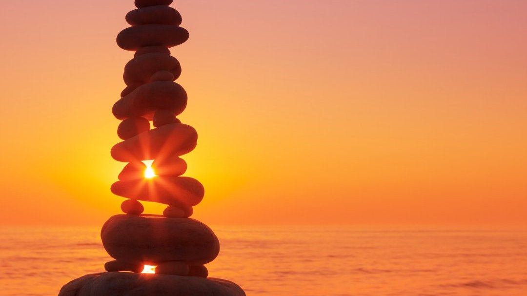 Pedras equilibradas no mar durante pôr do sol