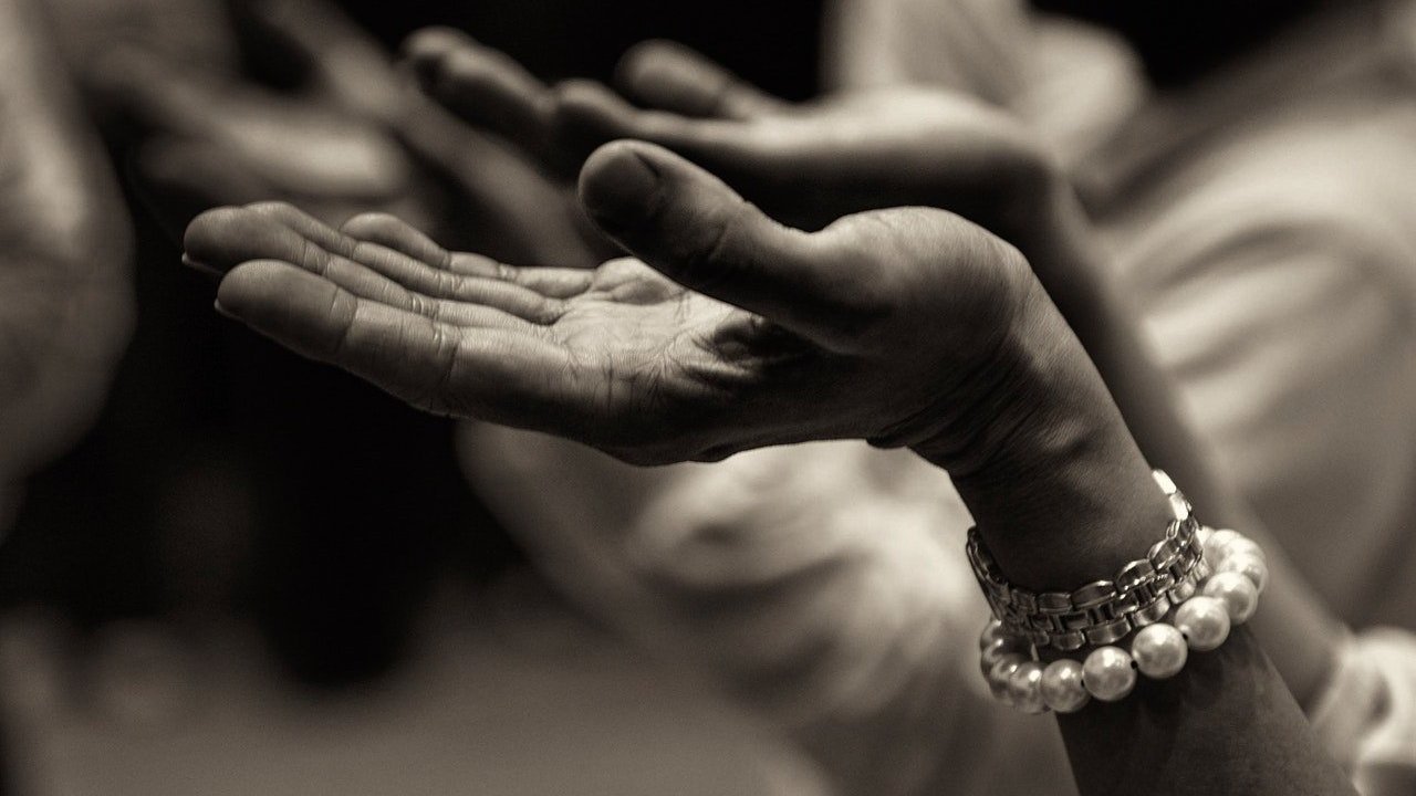 Imagem preto e branco de uma pessoa rezando.