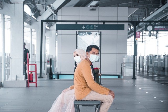 Casal asiático sentado em banco de aeroporto
